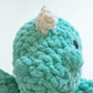 A close-up image of a plush toy with a textured, green-colored surface.