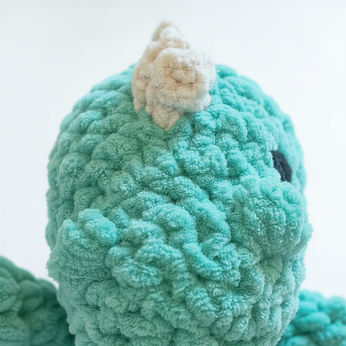 A close-up image of a plush toy with a textured, green-colored surface.